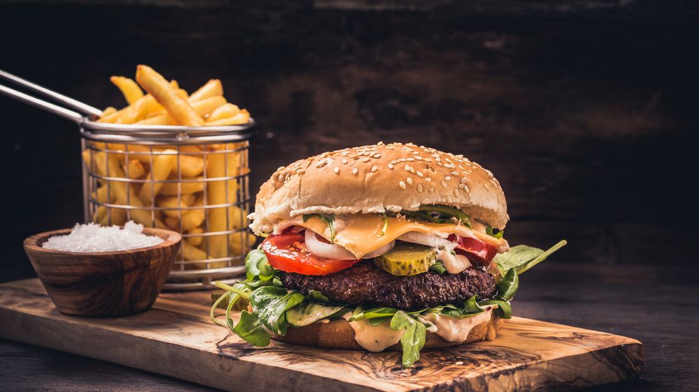 A burger that's large with cheese and fries