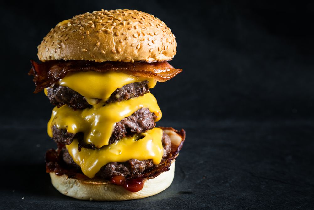 Goey cheeseburger that is tall with Bacon